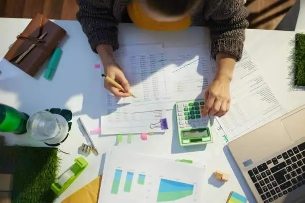 accountant woman with calculator and documents working in office.