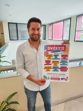 Fran Gasc&oacute;n, concejal de Juventud con el cartel de Divi&eacute;rtete Nin de agosto